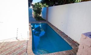a blue swimming pool next to a white wall at Grace Stays in Victoria Falls