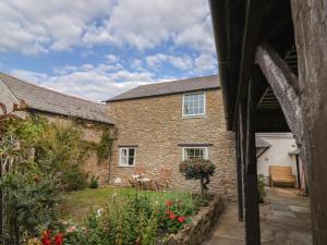 an outside view of a stone house with a garden at Vine Cottage in Burton Bradstock