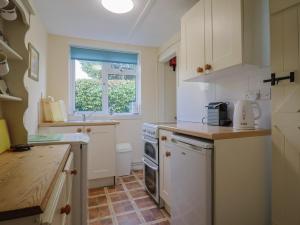 a kitchen with white appliances and a window at Vine Cottage in Burton Bradstock