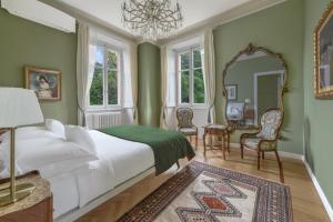 a bedroom with a bed and a mirror and chairs at Luxury Villa at Como Lake in Carate Urio