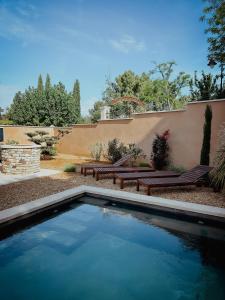 a swimming pool in a yard with two benches at Le mas de Roussillon chambre d'hôtes in Roussillon