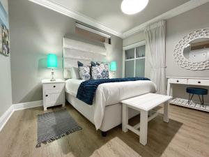 a bedroom with a bed and a table and a mirror at Coastal Hospitality - Beach Club 105 in Mossel Bay +32 photos