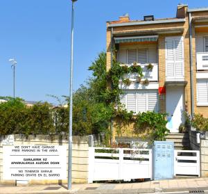 a house with a white fence and a sign in front of it at Chalet Baldissera in Estella