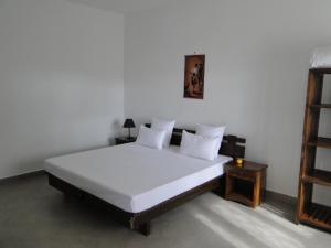 1 dormitorio con 1 cama con sábanas blancas y estante en HOTEL H1 ISALO, en Ranohira