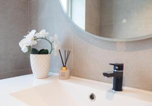 a bathroom with a vase of flowers on a sink at Apartment with exceptional view in Ålesund +38 photos