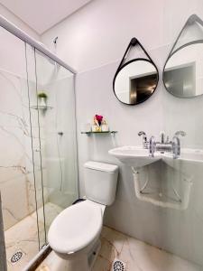 a bathroom with a toilet and a sink and a mirror at Hospedagem no Farol da Barra in Salvador