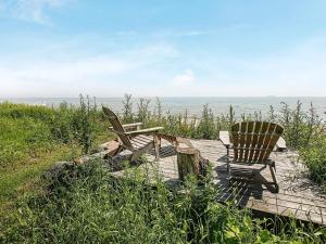 two chairs and a bench sitting on a boardwalk near the ocean at Seaside Bliss in Tranekaer - By Traum Ferienwohnungen in Fæbæk +40 photos