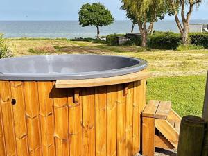 a wooden tub sitting in the grass near the ocean at Seaside Bliss in Tranekaer - By Traum Ferienwohnungen in Fæbæk