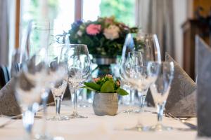a table with wine glasses and a vase with flowers at Haus am See in Niederdorla