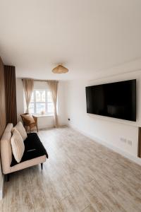 a living room with a couch and a flat screen tv at 3BR Detached Home, Driveway & Large Rear Garden in Hogganfield