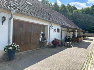 un edificio bianco con un garage in legno con fiori di Ferienzimmer Teiselsmühle Gehren Heideblick a Heideblick