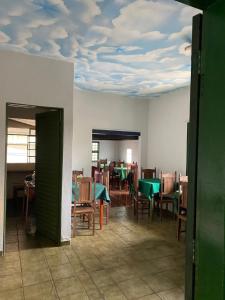 a dining room with green tables and chairs and a ceiling with a mural at Hotel Araguaia in Goiás