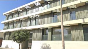 ein Bürogebäude mit einem Baum davor in der Unterkunft LUX BeACH in Praia da Barra
