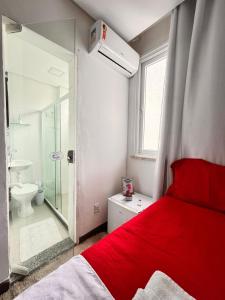 a bedroom with a red bed and a bathroom at Hospedagem no Farol da Barra in Salvador