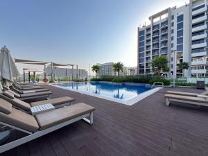 a swimming pool with lounge chairs and a building at The Comfort Cove Studio in Azizi Riviera 44 in Dubai