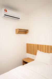 a bedroom with a white bed and a wooden headboard at TASEK 61 Guesthouse in Masai