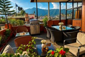 a patio with tables and chairs on a balcony with mountains at Nivas Boutique Home in Kathmandu