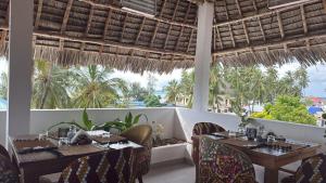 南威Ô TALIA Hôtel and SPA的一间设有桌椅的海景餐厅