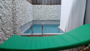 南威Ô TALIA Hôtel and SPA的房间里有一个带绿色长椅的游泳池