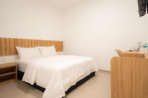 a bedroom with a white bed with a wooden headboard at TASEK 61 Guesthouse in Masai