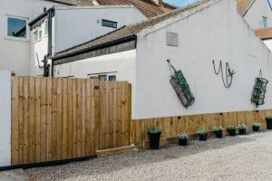 a fence next to a white building with potted plants at Withernsea 249 Stylish 2 Bed Apartment in Withernsea