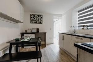 a kitchen with white walls and a table and a sink at Withernsea 249 Stylish 2 Bed Apartment in Withernsea