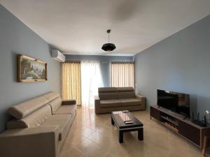 a living room with a couch and a tv at Skapeta Apartments in Sarandë