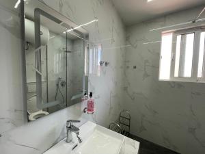 a white bathroom with a sink and a mirror at Skapeta Apartments in Sarandë +51 photos