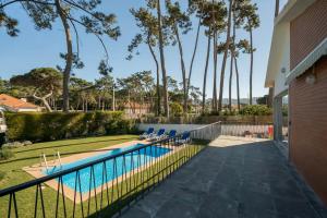 a swimming pool with chairs next to a house at Charming Family Villa in Colares in Colares