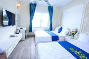 two beds in a hotel room with blue curtains at Platinum in Xóm Hương Phùng