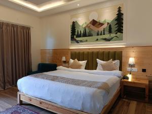 a bedroom with a large bed and a painting on the wall at Heryk Hillview Hotel in Dharamshala +131 photos