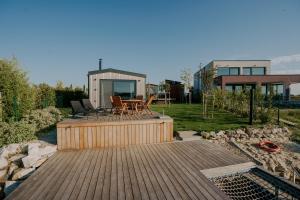Una terraza de madera con una mesa y sillas. en Kolokemp pri súkromnom jazere Boldog, en Senec