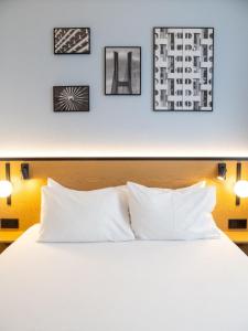 a bed with white pillows and three pictures on the wall at B&B HOTEL Wrocław Centrum in Wrocław