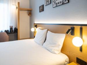 a hotel room with a white bed with two pillows at B&B HOTEL Wrocław Centrum in Wrocław +41 photos