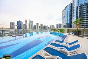 a swimming pool with chairs and a city skyline at Chic Studio Near Burj Khalifa in Dubai