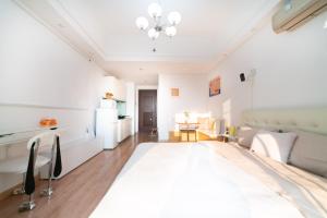 a white bedroom with a large bed and a couch at Xiao Meow B&B in Qingdao