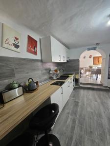 a kitchen with white cabinets and a wooden counter top at El Patio de Doña Tere in Villarta de San Juan