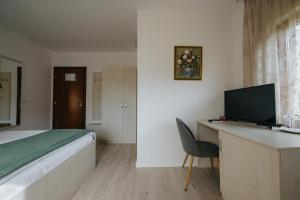 a bedroom with a bed and a desk with a television at Juliu's Panzio Csikszereda in Miercurea-Ciuc