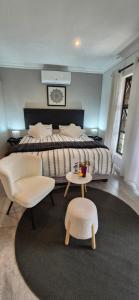a bedroom with a bed and two chairs and a table at Salty Soul Studio 70 in Roodepoort +50 photos