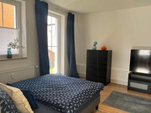 a bedroom with a bed and a tv and a window at Gutshof von Gemünden Ferienwohnung 3 in Bernau bei Berlin