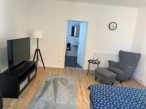 a living room with a bed and a chair and a television at Gutshof von Gemünden Ferienwohnung 3 in Bernau bei Berlin