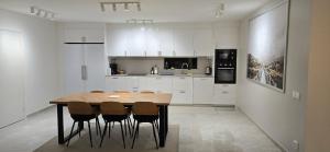 a white kitchen with a wooden table and chairs at Modern Full Comfort Villa in Agnesberg