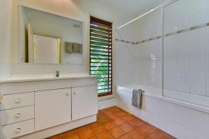 
a bathroom with a tub, sink, mirror and window at Heliconia Grove 9 in Hamilton Island

