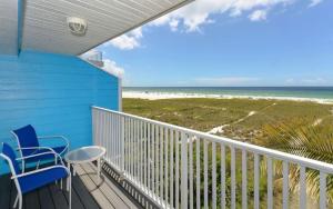 a balcony with two chairs and a table and the beach at Happy Blue Coconuts - South in Siesta Key