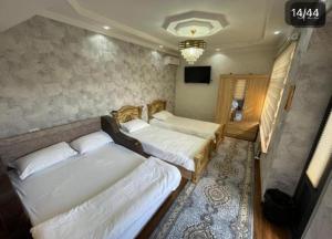 a bedroom with two beds and a television in it at Guesthouse Anora 1, Three minutes walk from Registan Square, The very Center of Samarkand in Samarkand