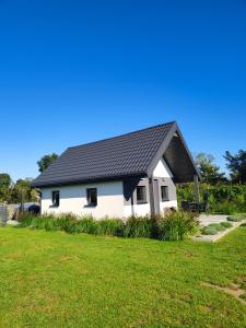 a white house with a black roof on a yard at Na Zaciszu in Cierzpięty +11 photos