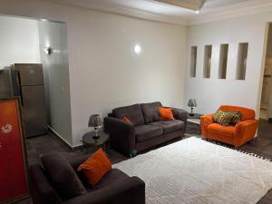 a living room with two couches and orange chairs at Two Bedroom Apartment- Senegambia Kololi- Kerr Ayo in Serekunda