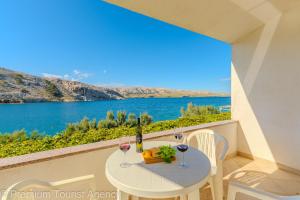 a table with wine glasses and a view of the ocean at Podvornica in Metajna