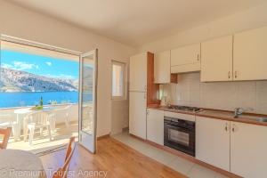 a kitchen with white cabinets and a view of the ocean at Podvornica in Metajna