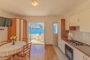 a kitchen and dining room with a table and a view of the ocean at Podvornica in Metajna +15 photos